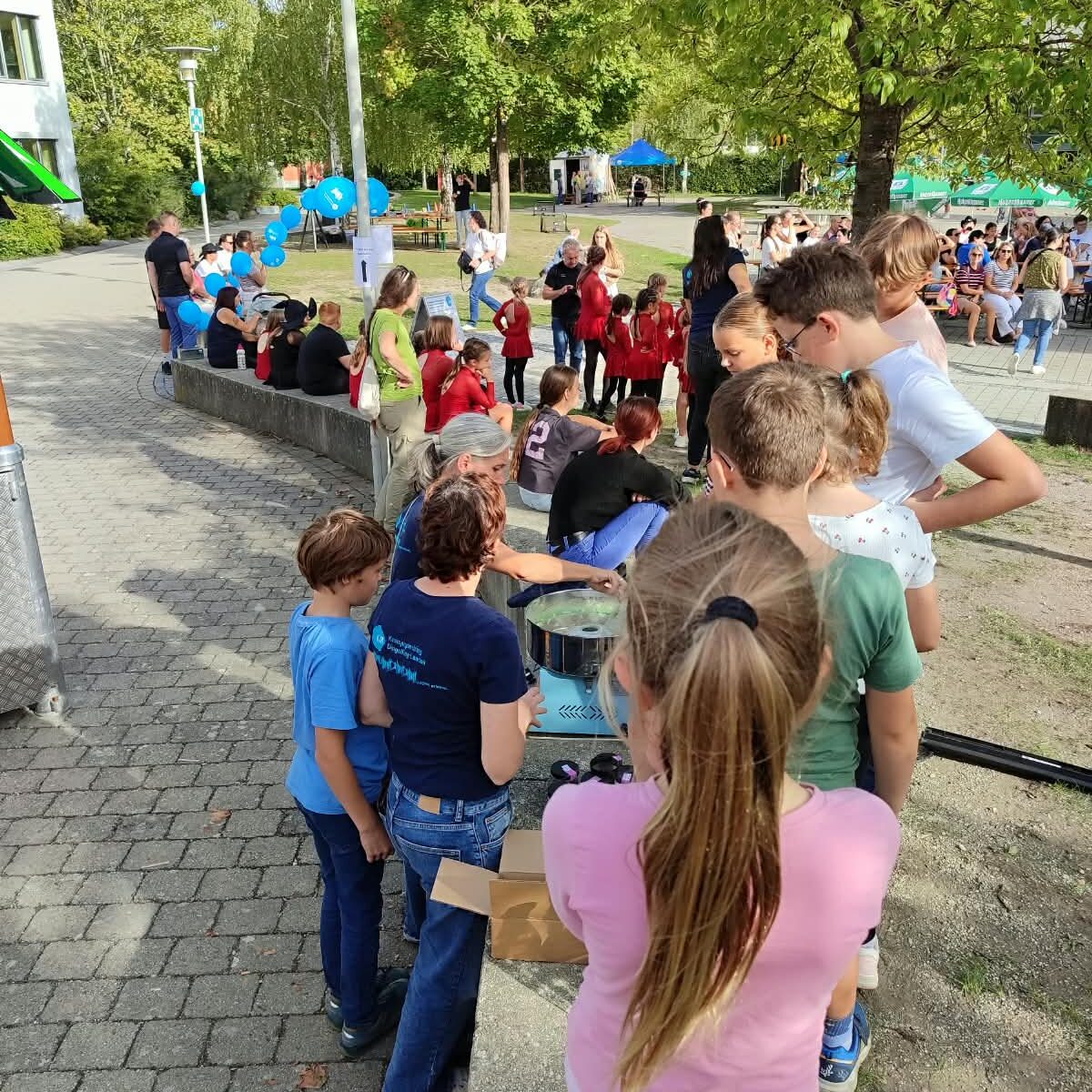 Kinder stehen bei der Zuckerwattemaschine bei der 80 Jahr Feier an
